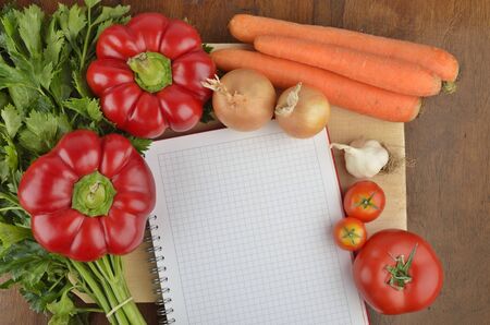 Grocery shopping list with notebook and fresh vegetablesの写真素材