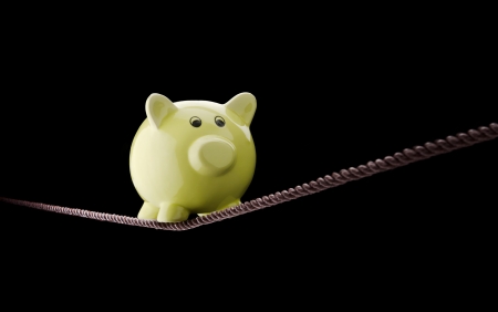 Piggy bank balancing on tightropeの写真素材