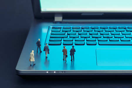 Miniature businessmen walking over the laptopの写真素材