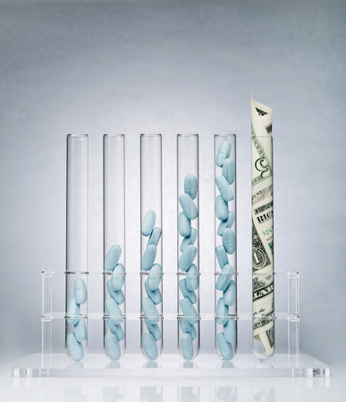 Rolled up US paper banknote in a test tube rack representing the costs of medical researchの写真素材
