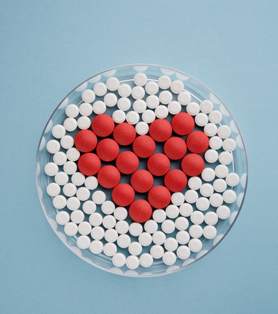 Petri dish with pills forming heart symbolの写真素材