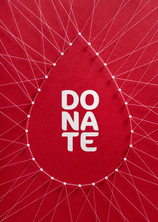 Donate blood concept. Network of pins and threads in the shape of a blood drop symbolising group effort and collaboration for saving lives.の写真素材