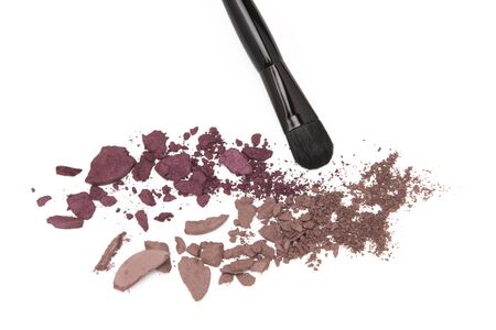 Close-up of crushed eyeshadow with makeup brush on white backgroundの写真素材