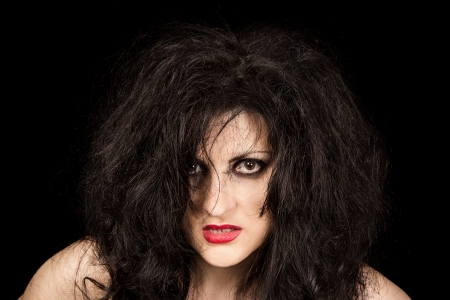 Portrait of black-haired woman with disheveled hair and ruby lipstick on black backgroundの写真素材