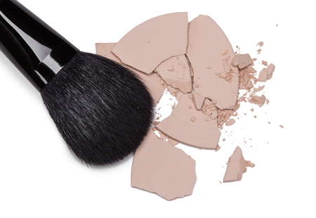 Close-up of crushed cosmetic powder with makeup brush on white backgroundの写真素材