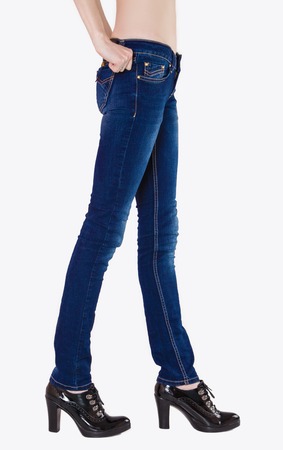 Shapely female legs dressed in dark blue jeans and black varnished boots with high heelsの写真素材