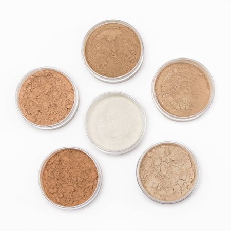 Jars filled with loose cosmetic powder different tones on white backgroundの写真素材