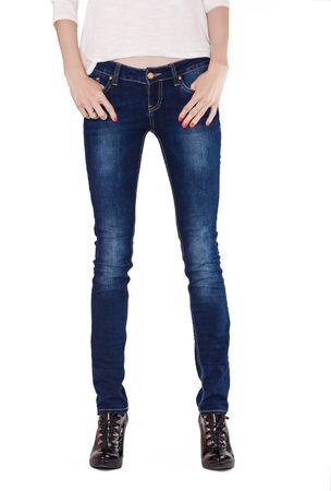 Shapely female legs dressed in dark blue jeans and black varnished boots on white backgroundの写真素材