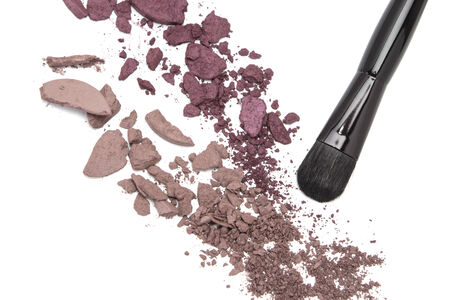 Close-up of crushed eyeshadow brown and plum shades with makeup brush on white backgroundの写真素材