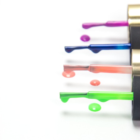 Brushes with multicolored nail polish, arranged in a row one after another on a white background, focus foregroundの写真素材