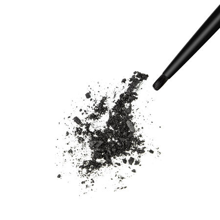 Closeup of crushed black shimmery eyeshadow with makeup brush on white backgroundの写真素材