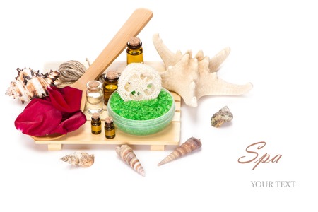 Spa accessories: sea salt with loofah, rose petals on the wooden spoon and bottles filled with aromatic oils on white backgroundの写真素材