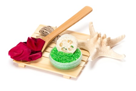 Spa composition: jar filled with sea salt, loofah, rose petals on the wooden spoon and starfish on white backgroundの写真素材