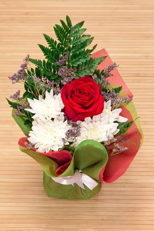 Beautiful floral bouquet. Arrangement of fresh red rose, white chrysanthemums, dried violet flowers and fern in wrapping colored paperの写真素材