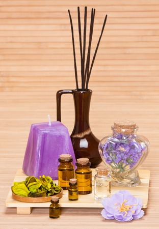 Aromatherapy accessories: floral petals, bottles filled with aromatic oils, incense sticks, candle on wooden surfaceの写真素材