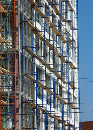 Facade of building under construction with scaffolding against blue skyの写真素材