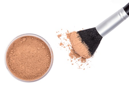 Makeup brush with open jar filled with loose cosmetic powder from above on white background