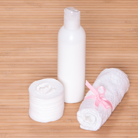 Container of facial cleansing milk with a towel and cotton padsの写真素材