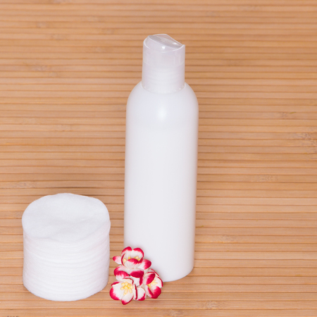 Facial cleaning and makeup removing cosmetic product with  cotton pads and small flowers on wooden surfaceの写真素材