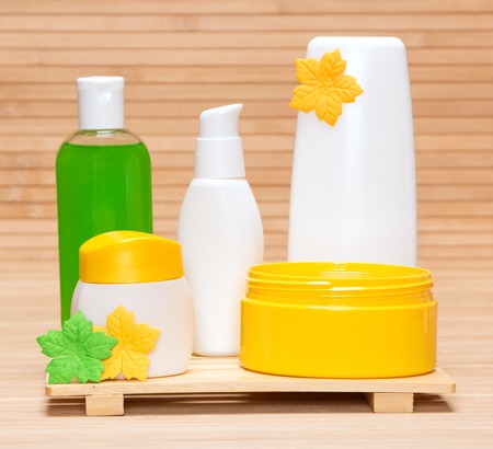 Jars with body care cosmetics and face cream on wooden surface. Yellow and green colorsの写真素材