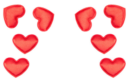 Frame of bright red fabric hearts on a white background