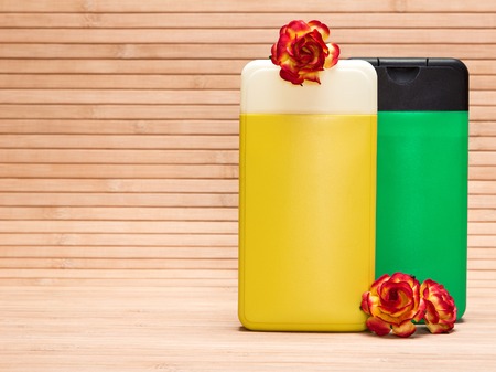 Cosmetic products for body care. Cleansing cosmetics. Closeup of bright yellow and green containers with flowers on wooden surface. Copy spaceの写真素材