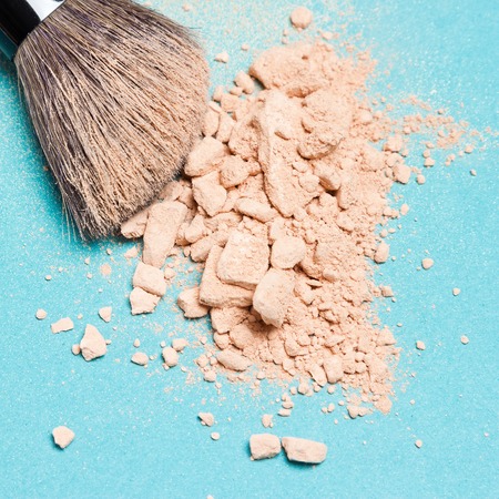 Close-up of makeup brush with crushed mineral matte compact powder on blue surface. Square cropの写真素材