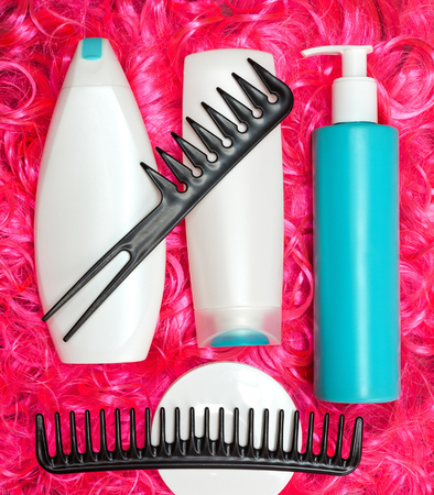 Curly hair care and styling products. Shampoo, conditioner, mask, moisturizing oil for facilitate combing hair with wide tooth combs on bright pink doll hairの写真素材
