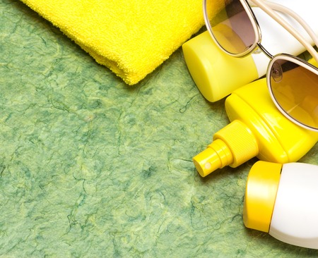 Cosmetic sunscreen products for face and body skin care, towel and sunglasses. Lotion, spray and cream. Cosmetics containing sun protection factor. Copy spaceの写真素材