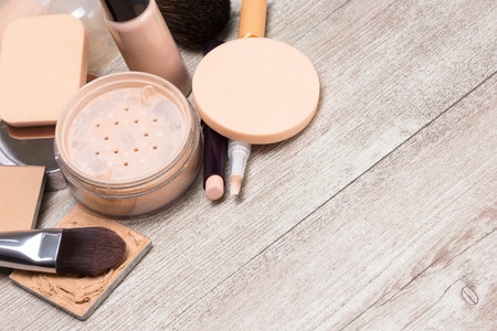 Beauty theme background. Various makeup products and accessories to even out skin tone and complexion. Concealers, foundation, powder, brushes, sponges on shabby wooden surface. Copy spaceの写真素材