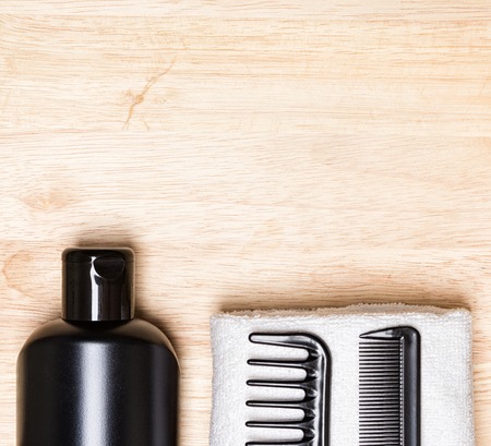 Hair care and styling background. Black bottle, wide tooth and fine tooth combs with white terry...