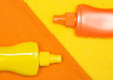 Close-up of sunscreen products bottles on terry towels. Cosmetics for safe tan
