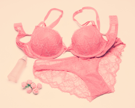 Sexy lace lingerie set with perfume spray and small roses. Push up bra and panties of soft pink color. Vintage toningの写真素材