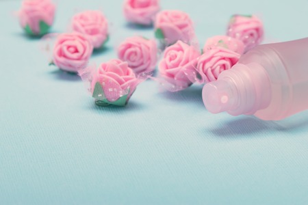 Perfume spray bottle with pink roses on blue textured background. Side view, very shallow depth of field. Vintage toning, copy spaceの写真素材