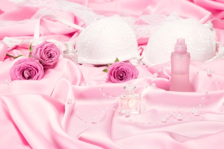 Perfumes with roses and women underwear on pink silk. Choice of fragrance for romantic date conceptの写真素材