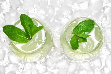 Refreshing drink with mint in large wine glasses surrounded by ice cubes. Close-up, top view. Cold mojito. Ice lemonadeの写真素材
