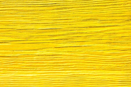Sunny texture of old cracked wooden board painted in yellow color. Wood surface backgroundの写真素材