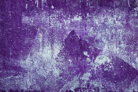 Old shabby concrete wall texture with cracked purple paint. Abstract grunge backgroundの写真素材