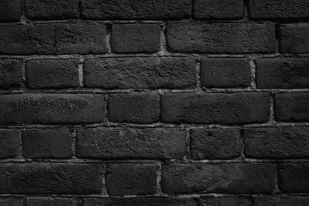 Black brick wall close-up texture. Rough aged brickwork. Dark grunge backgroundの写真素材