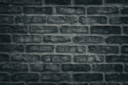 Dark grey brick wall close-up texture. Black masonry background. Rough aged brickworkの写真素材