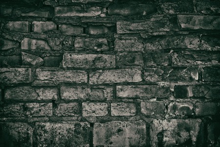 Dark gloomy old brick wall. Crumbled aged rough brickwork texture. Retro grungy background