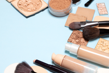 Makeup products for creating the perfect skin tone: concealer, primer, liquid foundation fluid with correcting, bronzing, golden shimmer, highlighting make-up powder. Copy spaceの写真素材