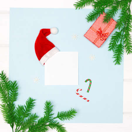 Christmas tree branches, gift box, Santa hat, snowflakes, candy canes and white blank paper card....