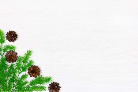 Green Christmas tree branches with pine cones on white wooden table, top view. Copy space. Christmas frame backgroundの写真素材