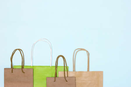 Craft paper merchandise bags on pastel blue background. Copy space. Shopping, sale minimal concept