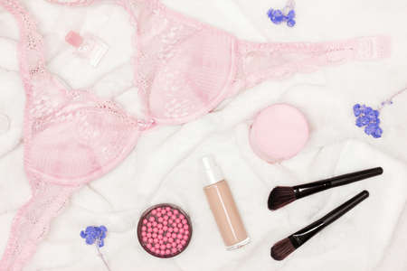 Pink lace bra, make-up cosmetics on white faux fur. Women essentials, female lifestyle conceptの写真素材