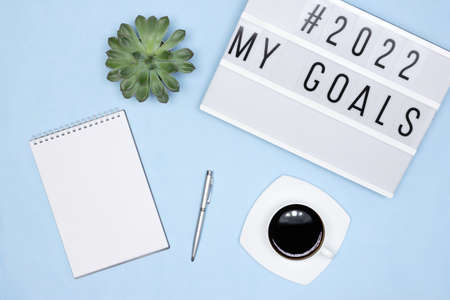 Open blank notebook page, pen, coffee cup, lightbox with My Goals text on office desk - top view. Plans for the coming year conceptの写真素材