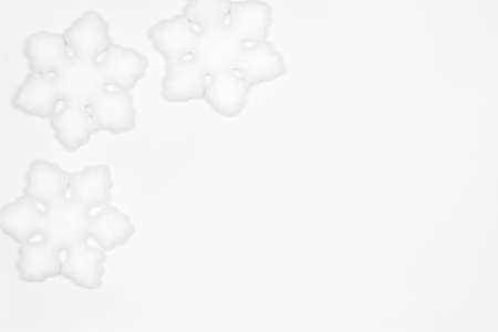 White snowflake decorations frame flat lay on white background. Copy space. Simple winter backdropの写真素材