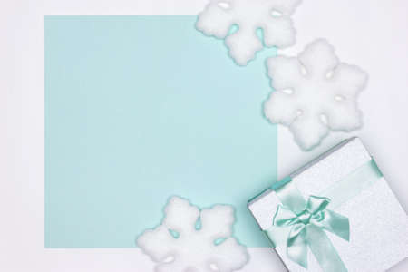 Gift box with white snowflake decorations top view. Copy space. Winter holidays pastel cyan...