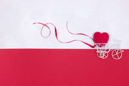 Small white toy bicycle delivering red velvet heart shaped gift box. Present for beloved woman,...